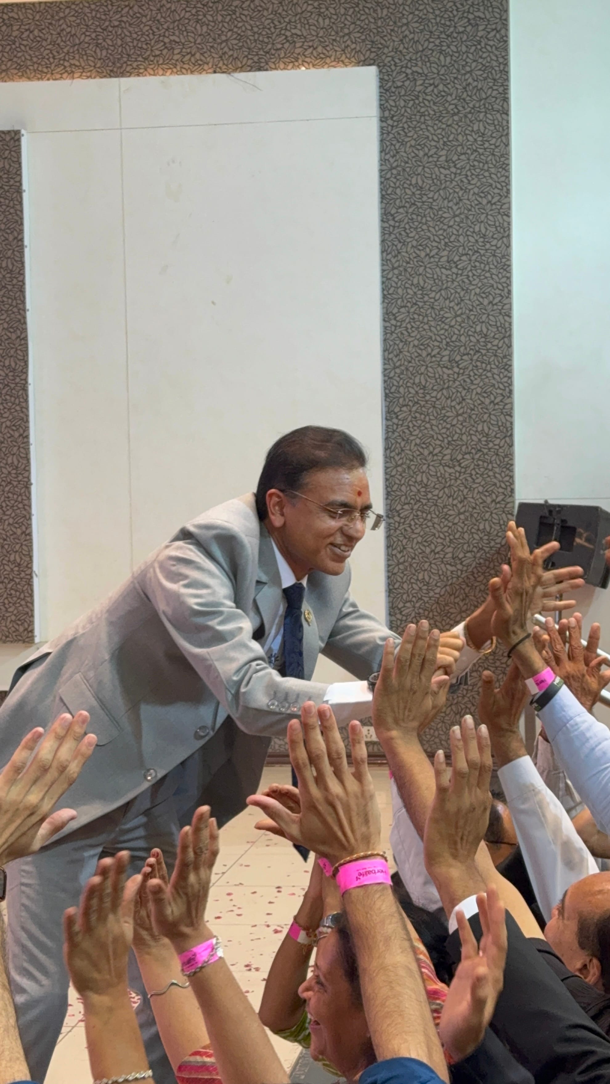 Amit Sarvaiya greeting attendees with a high-five at a community health event in Ahmedabad
